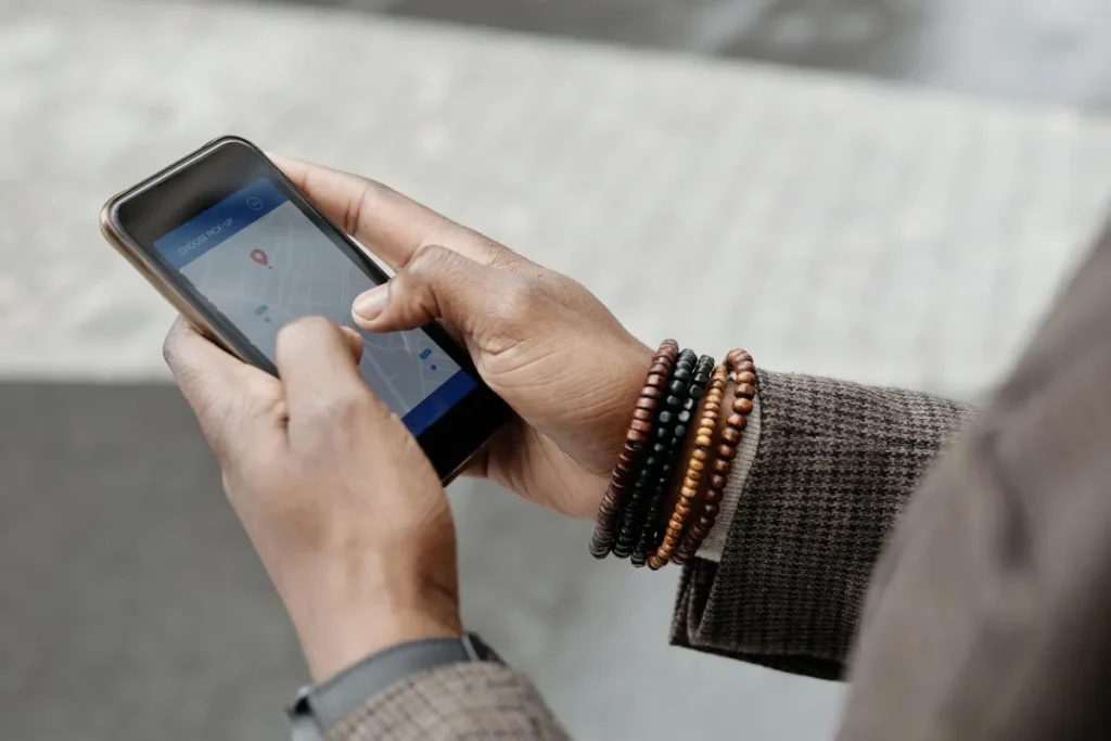 Tangan memegang smartphone yang menampilkan aplikasi GPS untuk melacak lokasi